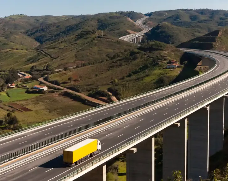 Yellow lorry driving on empty bridge 