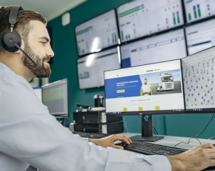 man with headset working at computer with multiple screens